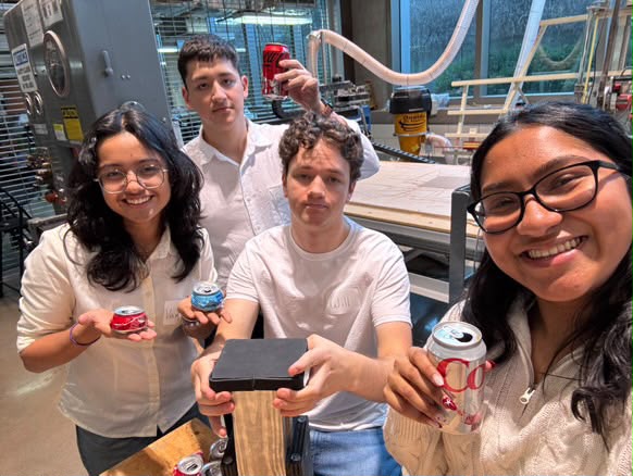 Team holding crushed cans in the makerspace